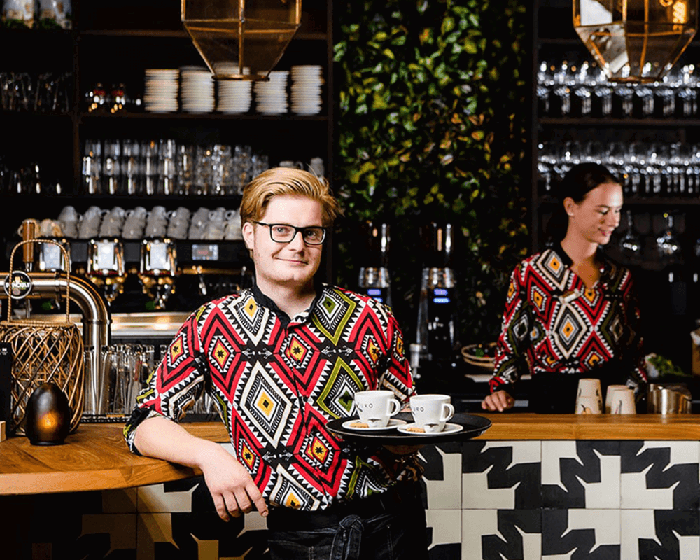 Outfit voor Beekse Bergen Medewerkers van Beekse Bergen aan het werk in de horeca van het safaripark gekleed in full custom made-bedrijfskleding met unieke Afrikaanse print door Outfit company wear