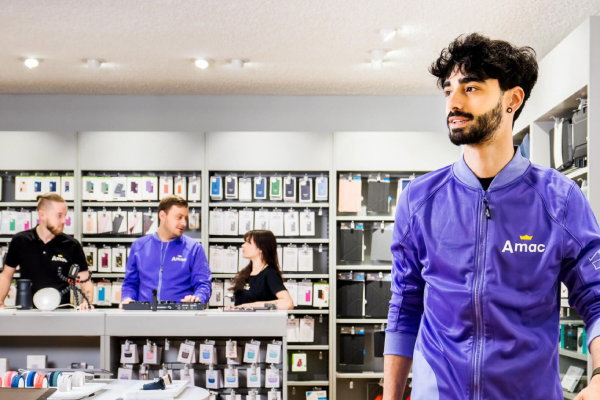 Outfit bedrijfskleding voor Amac – branche retail en leisure – 600×400 Medewerkers van Amac aan het werk in de winkel gekleed in een zwarte Amac-polo, T-shirt en full custom made Amac-jasje in de kenmerkende paarse Amac-kleur