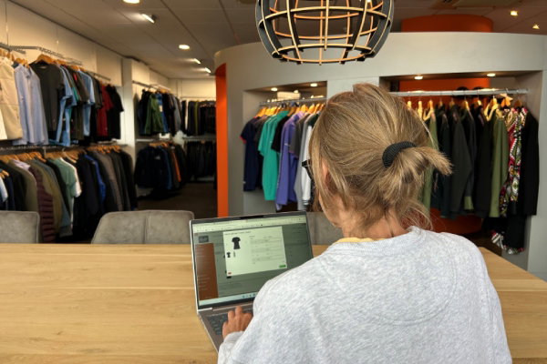 Persoon besteld bedrijfskleding in de persoonlijke webshopomgeving in de showroom van Outfit